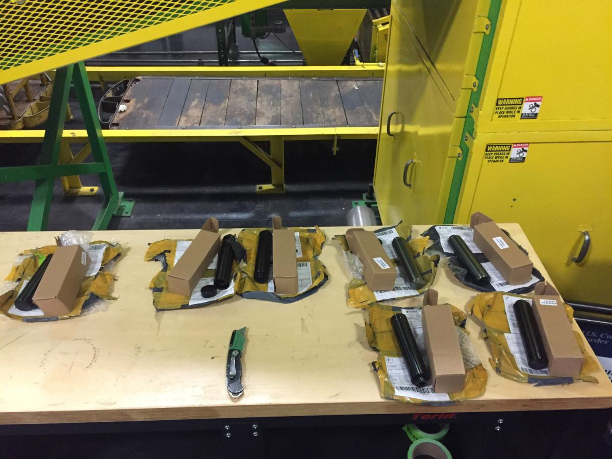 Geöffnete Postpakete aus China mit Pappschachteln auf einem Tisch in einem internationalen Zollpostzentrum