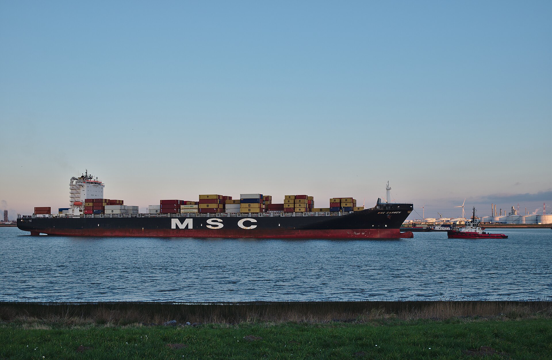 Containerschiff wird auf der Schelde von einem Schlepper zum Hafen Antwerpen geführt, Belgien